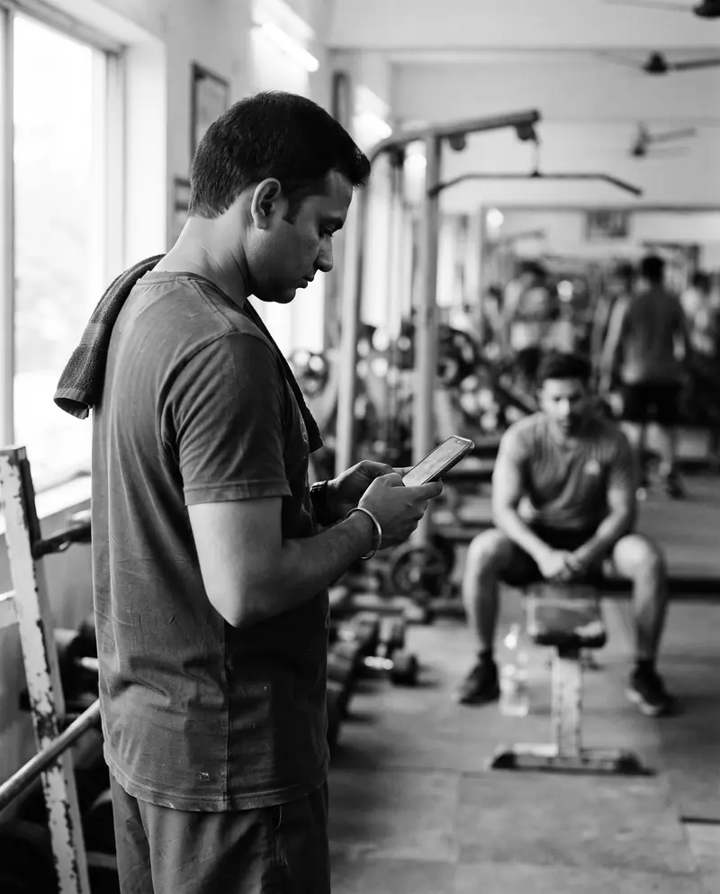A personal trainer checking the session plan on a phone while a client rests between sets